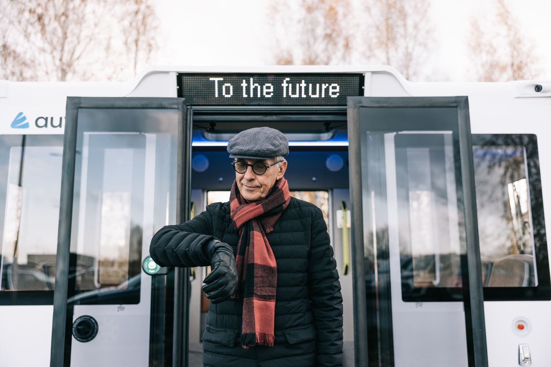 Man standing in front of self-driving bus labelled To the Future created by Estonian startup Auve Tech