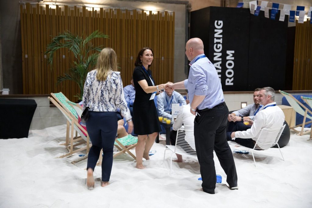 Group of professionally dressed people meeting on deckchairs in the sand at a conference
