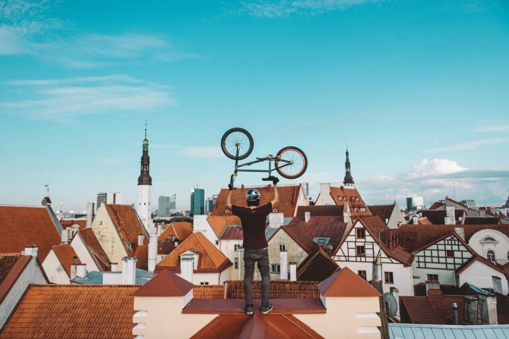 Man holding bicycle above his head looking over the rooftops of Tallinn Old Town
