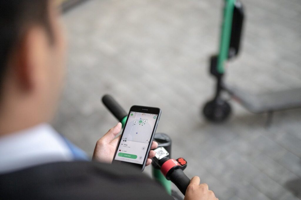 Man scanning Bolt scooter on app on his smartphone on the street.