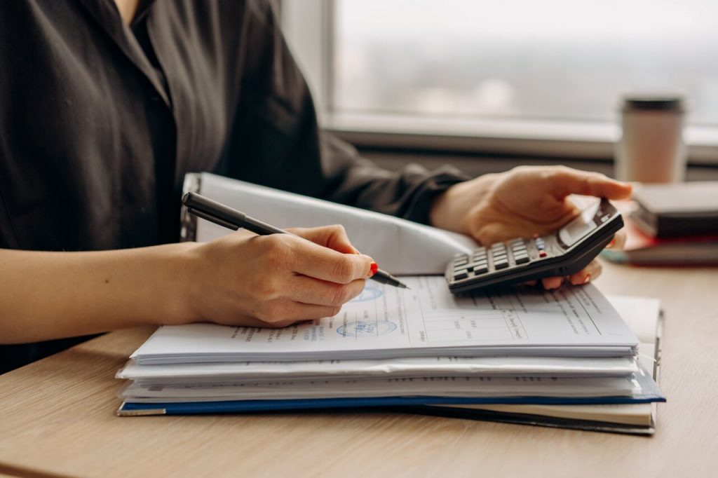 Personal in long sleeve shirt holding calculator to work out their digital nomad tax