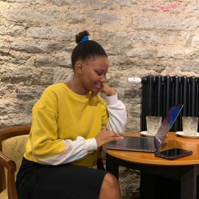 Digital nomad and e-resident Fifi Matlatse in a yellow sweater working on her laptop