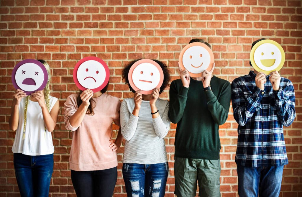 Five people holding smiley faces to rate their satisfaction with client banking services