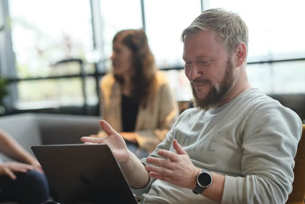 Man sitting and gesturing on an online call on laptop remote working
