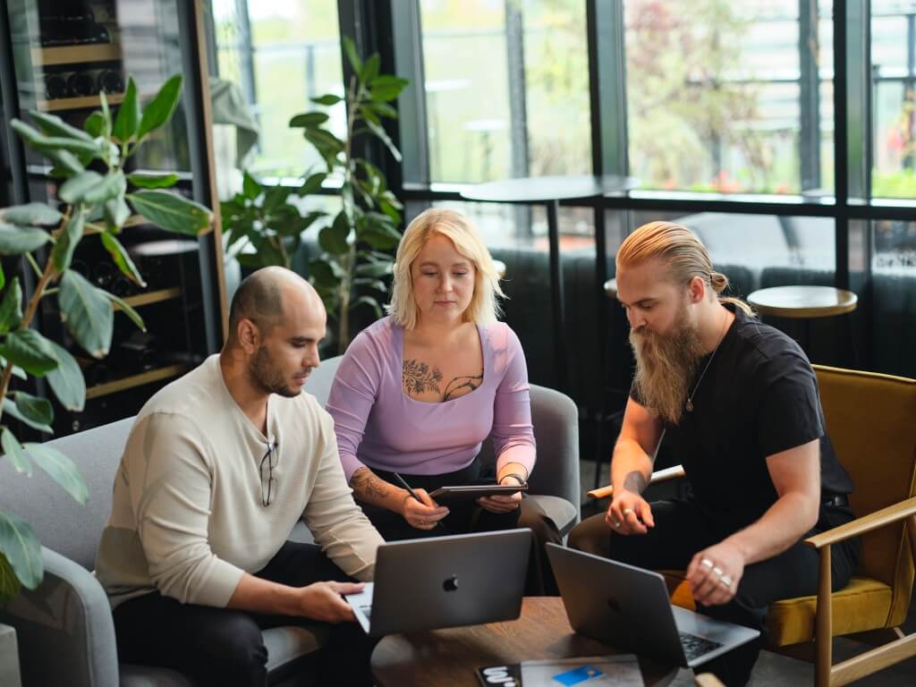 Woman and two men in a meeting looking at a laptop and discussing corporate income tax - a hot topic among the e-resident community