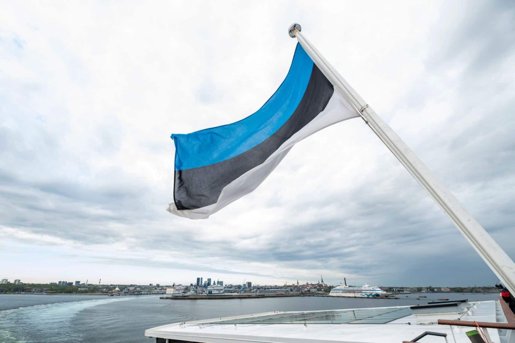 Estonia VAT concept symbolised by Estonian flag waving over the city of Tallinn