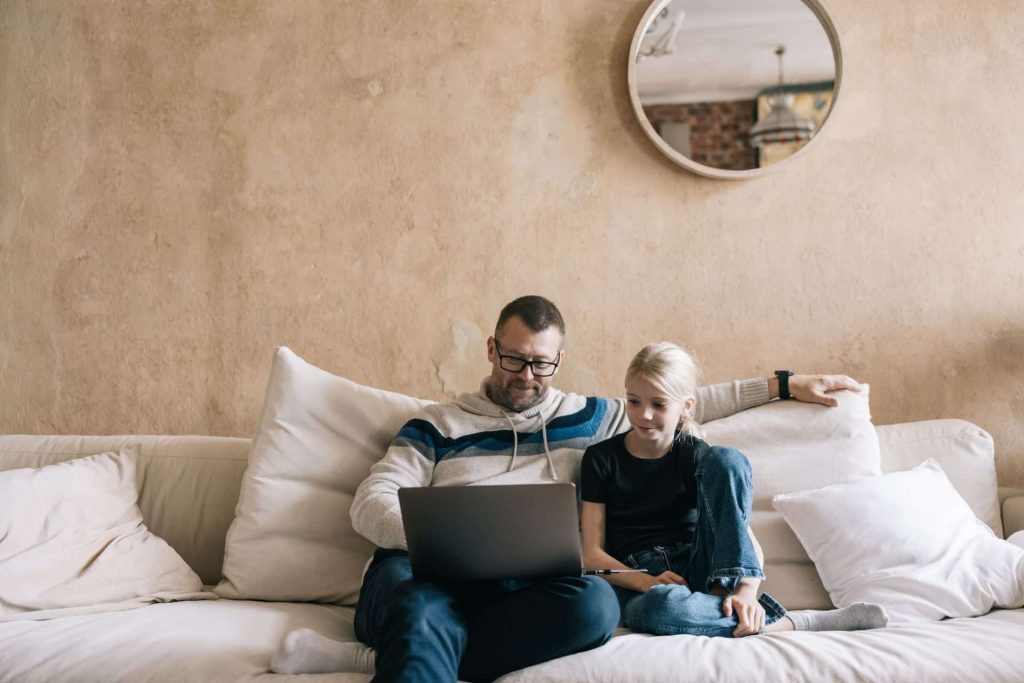 A father uses Estonia's e-government services from laptop with daughter on sofa