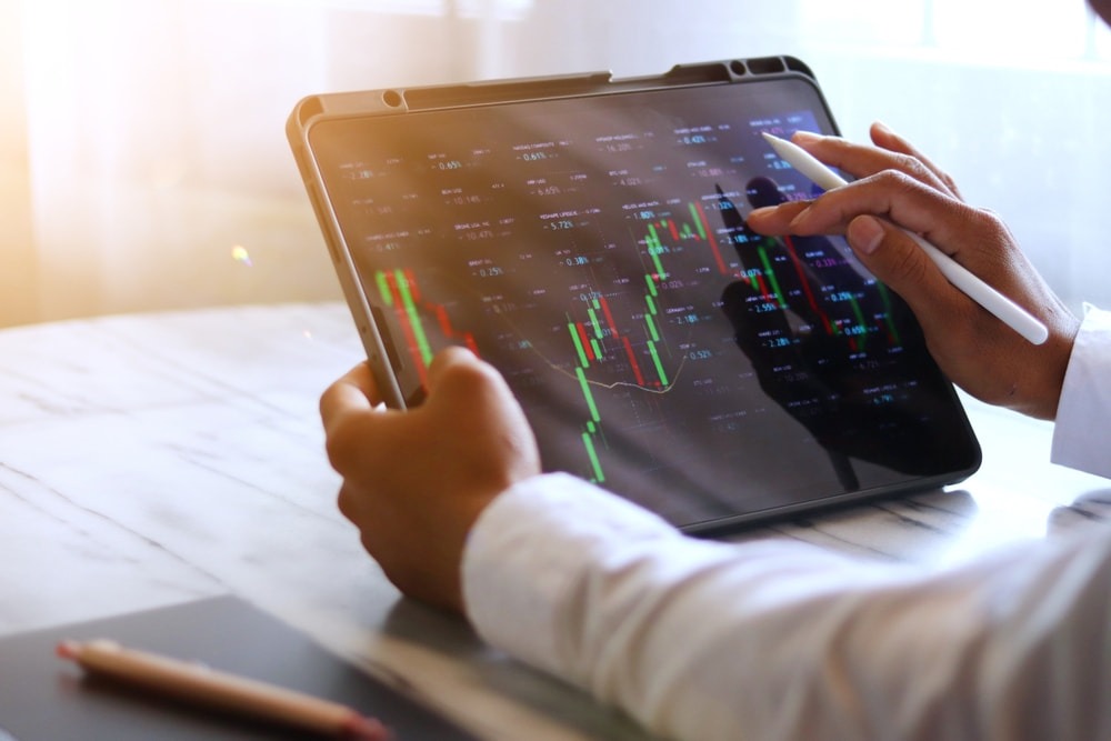 A man uses a holding company to invests in stocks from a tablet