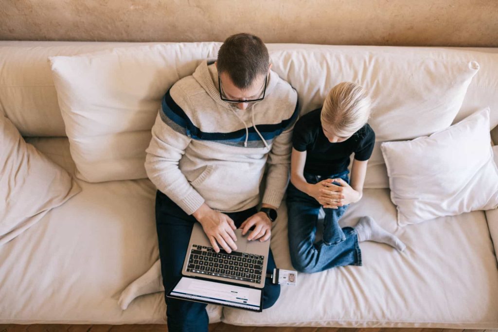 A father shows his daughter how digital ID works on a laptop