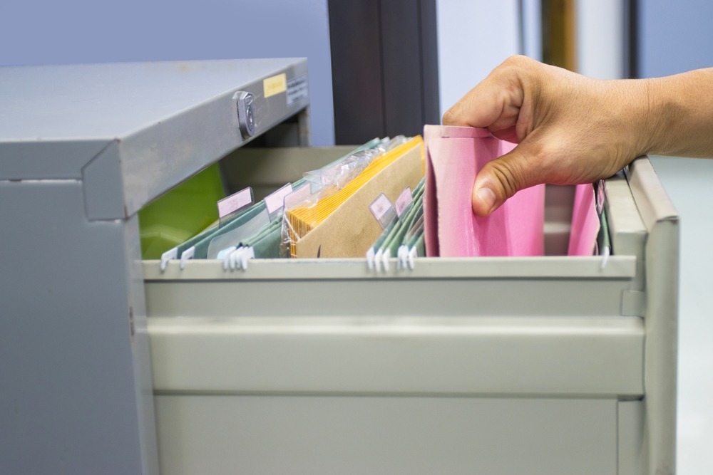 A hand searching through a file cabinet